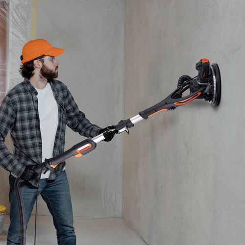 Drywall sander in action on wall